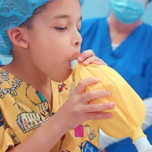 a child in a hospital gown breathing from a bag